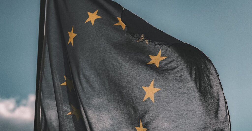European Union flag gently waving on a flagpole against a cloudy sky, symbolizing unity and patriotism.