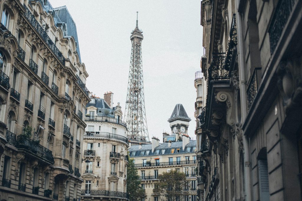 Visiter Paris en 4 jours : entre culture, gastronomie et romantisme 🇫🇷 Scenic view of the Eiffel Tower framed by classic Parisian architecture on a charming street.