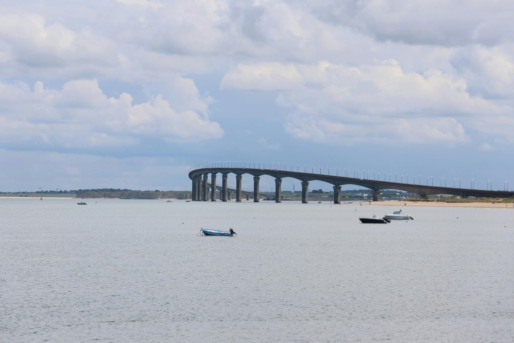 L’île de Ré en 2 jours : entre océan, charme et douceur de vivre 🇫🇷 A serene view of the Ile de Re bridge stretching over a calm sea with scattered boats.