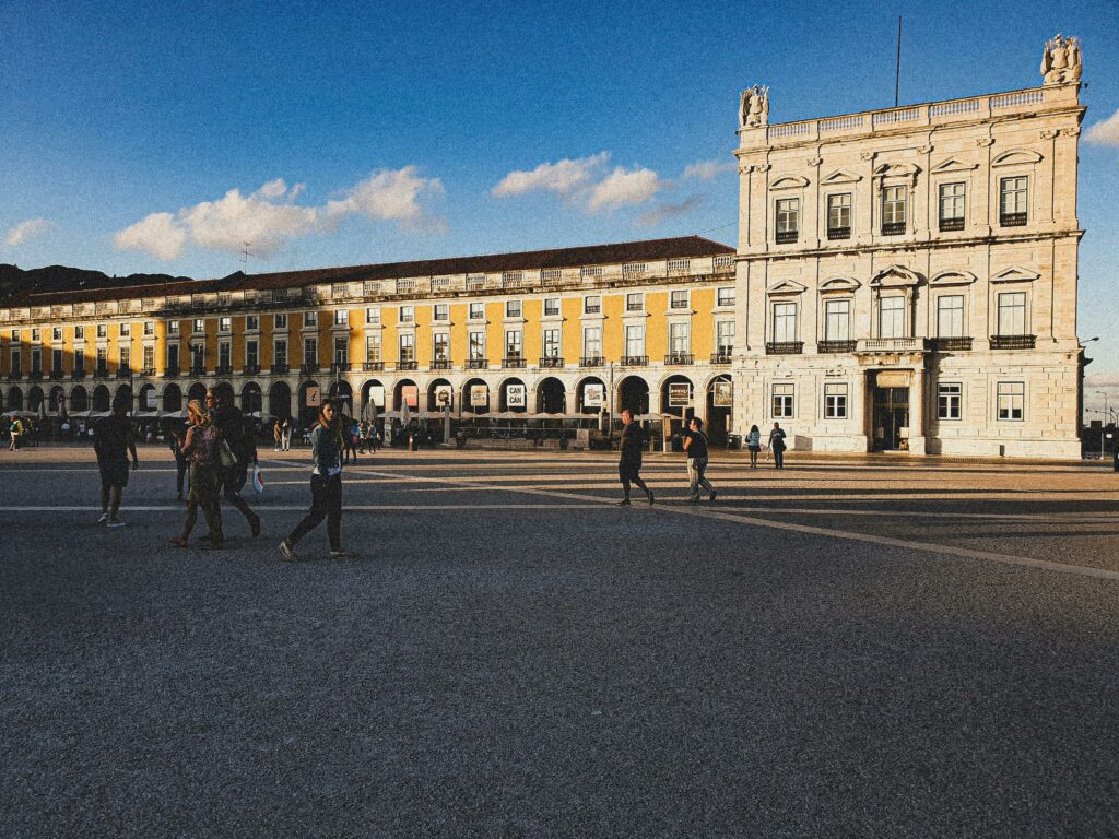 Lisbonne en 4 jours : itinéraire complet et incontournables 🇵🇹 Prominent view of Praça do Comércio in Lisbon with people strolling under a clear blue sky.