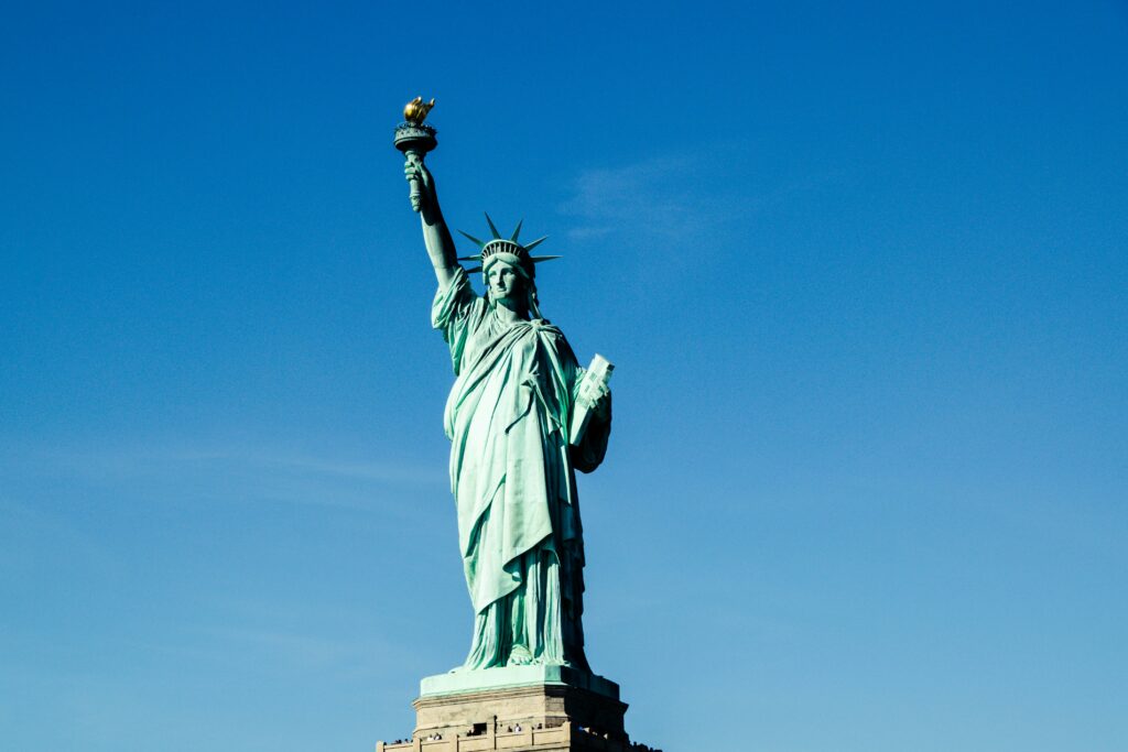 Iconic Statue of Liberty with vibrant blue sky backdrop, symbolizing freedom and hope.